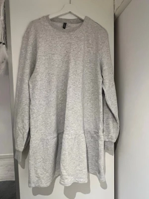 Grå sweatshirtklänning H&M - Mysig grå sweatshirtklänning från H&M med rund halsringning och långa ärmar. Klänningen har en avslappnad passform och är tillverkad i mjuk bomullsmix, perfekt för chill dagar. Enkel och stilren design utan mönster eller detaljer.