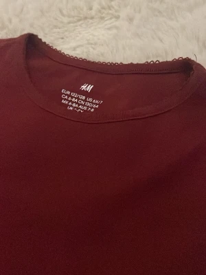 vinröd  långärmad tröja från  H&M - En enkel och stilren vinröd  långärmad tröja från H&M. Tröjan har rund halsringning med en liten dekorativ kant och är gjord i ett mjukt, stretchigt material som känns skönt mot huden. Säljer då den inte passar mig längre ❤️