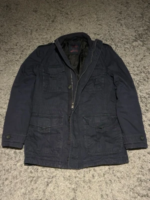 Field jacket från esprit - Snyggparkasjacka med flera praktiska fickor framtill och dragkedja samt knappar. Jackan har en klassisk rak passform och är fodrad för extra värme. Materialet är slitstarkt och perfekt för kyligare dagar.