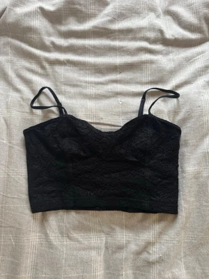 Svart spetslinnetopp från H&M - Trendig svart linnetopp från H&M:s DIVIDED-kollektion. Toppen är ärmlös med tunna axelband och har ett snyggt spetsmaterial som ger en extra detalj. Hör av dig vid frågor ❤️