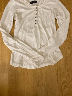Vit långärmad tröja från Abercrombie & Fitch - En vit långärmad tröja med knappar. Köpt på Vinted men passade mig inte.   Skriv om ni har några funderingar✌️🩷 Tröjan är i storlek S men skulle säga att den sitter som M beroende på hur tajt man vill att den ska sitta! Säljer den för dyrt pris då jag köpte den för ungefär samma summa!🙌