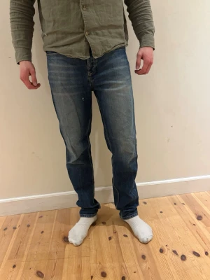 Blå raka jeans med tvättade detaljer - Säljer ett par klassiska blå jeans med raka ben och snygga tvättade detaljer framtill. Jeansen har fem fickor och normal midja. Perfekta för en avslappnad och stilren look. Materialet är denim i bomull.