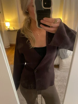 Mörkbrun kofta med knappar - Säljer denna jättefina mörkbruna tröja/kofta med två knappar framtill. Den har en djup v-ringning, perfekt att ha ett linne under! Ärmarna är vida och långa!