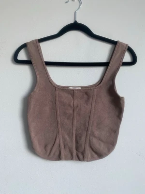 Nougatfärgat ribbat linne - Riktigt snyggt ribbat brunt/nougat linne från H&M. Breda axelremmar och cropped fit. Storlek small. 