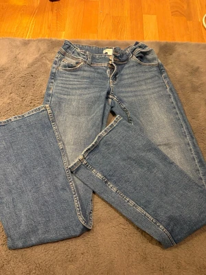 Blå bootcut jeans GinaTricot - Säljer ett par blå jeans, bootcut. Jeansen har detaljerade sömmar, samt knappar på bakfickorna. Väldigt bra skick 