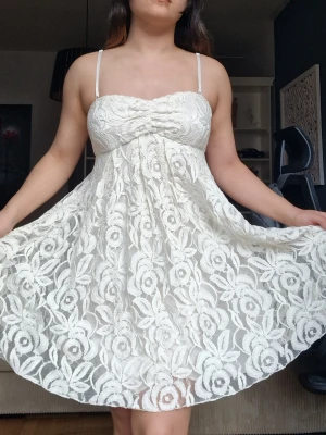 Vit spetsklänning med axelband - Supersöt vit kort klänning med tunna axelband och vackert blommigt spetsmönster. Klänningen har en söt bystdetalj och är perfekt för sommarens alla tillfällen. Lätt och luftig modell som ger en romantisk vibe. Har aldrig använts och är för stor för mig. Storleken är närmare en S/M.