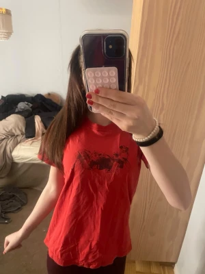 Röd t-shirt med svart tryck - Säljer en röd t-shirt med coolt svart tryck på bröstet. T-shirten har klassisk passform och korta ärmar, perfekt för dig som gillar en avslappnad och enkel stil. Materialet känns mjukt och bekvämt mot huden. Superfin hör av dig för frågor💕❤️