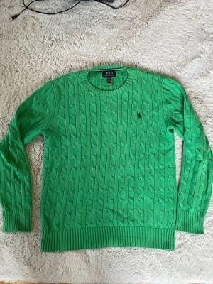 Grön kabelstickad  Polo Ralph Lauren - Tjena, säljer den här gröna kabelstickade tröjan ifrån Ralph lauren. Tröjan har använts ca 15 gånger. Barnstorlek L men passar som XS. Kontakta för fler bilder eller frågor!