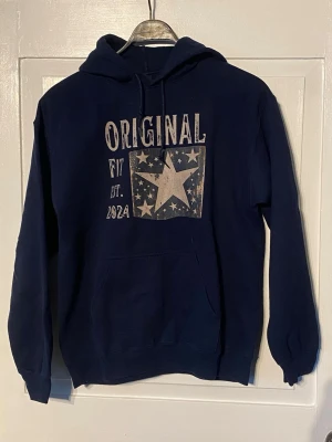 Mörk blå hoodie med tryck ”Original fit” - Mörkblå hoodie med ”Original fit EST. 2024” tryck på mage/bröst. Magficka och luva. I gott skick, knappt använd 
