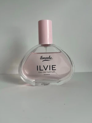 Ilvande ILVIE Eau de Parfum - Snygg parfymflaska från Ilvande med doften ILVIE Eau de Parfum för kvinnor. Flaskan är ljusrosa med genomskinligt glas och har en modern, mjukt formad design samt ett matchande rosa lock. Perfekt för dig som gillar eleganta och feminina dofter. 100 ml 