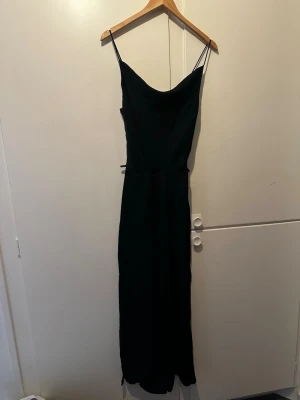 Svart byxdress från Zara  - Stilren svart byxdress från Zara Basic med tunna axelband och två slutar på vardera sida av benen och är perfekt för dig som gillar minimalistisk stil. Tillverkad i ett mjukt material som känns bekvämt mot huden.