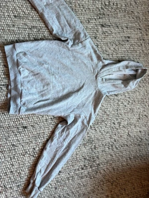Ljusgrå basic hoodie med ficka - En enkel och stilren ljusgrå hoodie med huva och stor magficka. Tillverkad i mjukt sweatshirtmaterial och har ribbade muddar vid ärmar och nederkant. Perfekt för en avslappnad look och passar till det mesta.