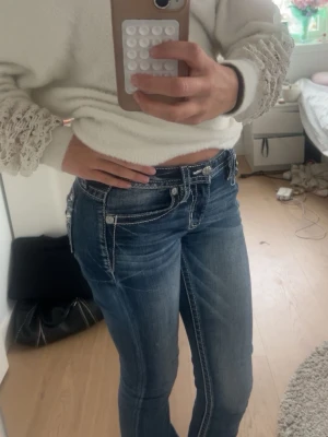 Miss me jeans - Säljer ett par blå bootcut miss me jeans med tydliga vita kontrastsömmar och låg midja. Jeansen har klassiska fem fickor och snygga slitningar framtill för en trendig look. Perfekta för dig som gillar en avslappnad men ändå stilsäker stil. Jag är 174 lång och dom perfekta för mig.
