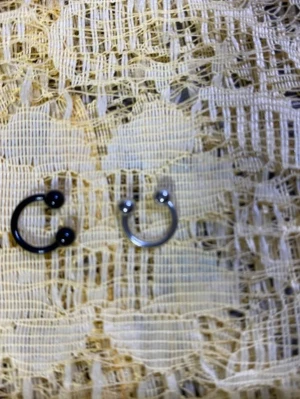 Två hästskoformade piercingringar - Säljer två hästskoformade piercingringar, en i svart metall och en i silverfärgad metall. Båda har kulor i ändarna och passar perfekt som smycke till exempelvis näsa eller öra. Stilrena och enkla att matcha med olika looks.