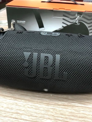 JBL Xtreme 3 bärbar högtalare svart - Kraftfull bärbar högtalare från JBL i svart med robust tygmaterial och gummerade detaljer. Cylindrisk form med stora JBL-loggor på sidan och praktisk bärrem. Perfekt för att ta med sig musiken överallt och levererar riktigt bra ljud och bas.