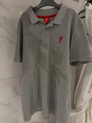 Liverpool pikétröja - Säljer nu denna jättefina pikétröja i storlek M, som luktar misstag & slibbigt hotellrum. Fint skick utöver stanken av ladies night (kemtvättar innan jag postar🤗)  finaste märket i fotboll men som tyvärr har dragits med i leran.. har en likadan i mörkgrått, för mer info & bilder kom PM💗
