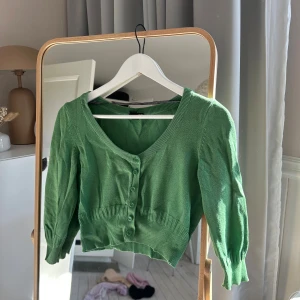 Grön bolero/ kofta från hm - Snygg grön bolero från hm.  Den har trekvartsärmar och ribbade detaljer vid midjan och ärmsluten. 