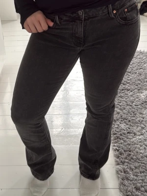 Svarta bootcut jeans med broderi - Snygga svarta bootcut jeans med diskret tvättad look och broderade detaljer på bakfickorna. Klassisk femficksmodell med knapp och dragkedja framtill. Jeansen har en rak passform som smalnar av över låret och släpper vid vaden. Perfekta till sneakers eller boots. Fina byxor men tyvärr för stora i midjan för mig.