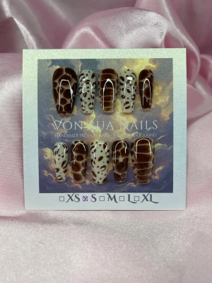 Feral (S);Medium Ballerina - Unika handgjorda press-on naglar i S: 15 mm, 11,5 mm, 12 mm, 11 mm, 9 mm . Naglarna har ett coolt animalprint- mönster i brunt och beiget med glansig finish. Formen är medium långa ballerina och är perfekta för dig som vill sticka ut med trendiga naglar.
