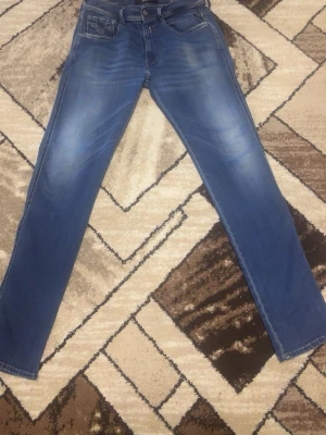 Blå slim fit jeans med slitningar - Snygga blå slim fit jeans med lätt slitna detaljer och klassisk femficksdesign. Jeansen har en medelhög midja och smal passform hela vägen ner. Perfekta för en trendig och avslappnad look.