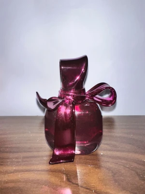 Ricci Ricci parfym 50 ml Nina Ricci - Ricci Ricci från Nina Ricci är en parfym i en elegant glasflaska med metallic mörkrosa färg och en unik rosettformad kork. Flaskan har en lyxig och lekfull design som verkligen sticker ut på hyllan. Perfekt för dig som gillar snygga detaljer och vill ha något extra.
