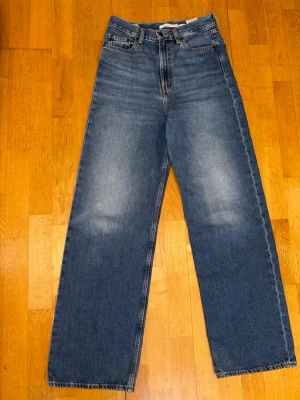 Levi’s Premium High Loose Jeans W28 L33 – Nyskick - Snygga Levi’s Premium High Loose jeans i klassisk blå tvätt. Hög midja och bred rak passform/wide leg som sitter väldigt fint.  Jeansen är i nyskick och endast använda någon enstaka gång. Inga slitningar eller anmärkningar.  Storlek: W28 L33 Modell: High Loose Färg: Blå denim  Mått (ca):  * Midja: 37 cm * Innerbenslängd: 80 cm * Ytterlängd fram: 113 cm * Ytterlängd bak: 116 cm  Material: 77% bomull 23% hampa
