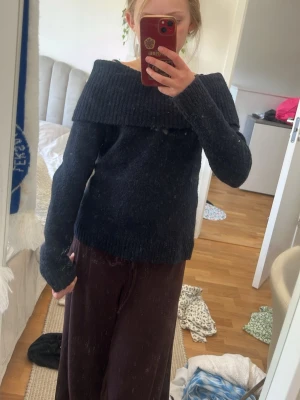 Blå off shoulder stickad tröja - Mysig blå stickad tröja med bred off shoulder-krage och långa ärmar. Tröjan har en ribbstickad kant upptill och är perfekt för lager-på-lager-stil. Materialet ser ut att vara mjukt och lite luddigt, vilket ger en avslappnad vibe.