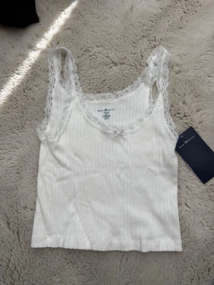 Brandy Melville topp - Supersöt linne med spetsdetaljer, helt ny med prislapp från Brandy Melville. Onesize. Nypris 198kr, säljer för 100kr. 
