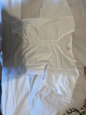Vit blus med broderade ärmar H&M - Söt vit blus från H&M med v-ringning och korta ärmar i broderad spets. Blusen har fina detaljer med rynk framtill och luftiga ärmar med blommönster. Perfekt för en fräsch och somrig look.