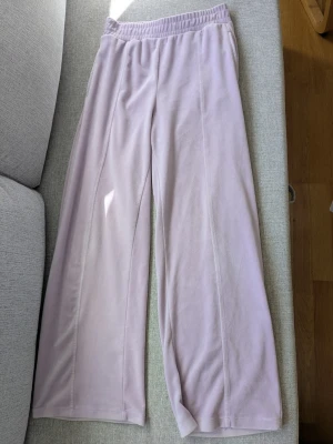 Ljuslila mjukisbyxor från Lindex - Mysiga ljuslila mjukisbyxor från Lindex med bred resår i midjan och raka, vida ben. Tillverkade i mjukt material som känns skönt mot huden. Perfekta för chill dagar hemma eller när du vill vara extra bekväm.