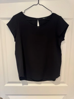Svart topp från ONLY med kort ärm - En stilren svart topp från ONLY i storlek 34. Toppen har rund halsringning, korta ärmar och en enkel, klassisk design. Perfekt att matcha med olika outfits för en clean look.