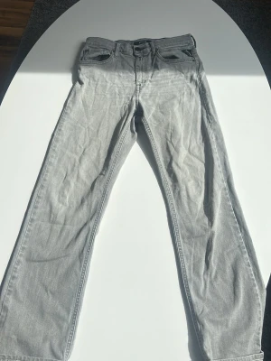 Gråa replay jeans  - Snygga grå jeans från Replay  med rak passform och klassisk femficksdesign. Jeansen har bälteshällor och dragkedjegylf. Perfekta för en avslappnad och trendig look.