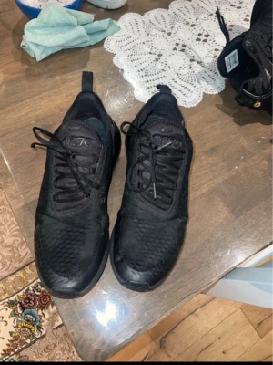 Svarta Nike Air Max 720 sneakers - Säljer ett par helsvarta Nike Air Max 720 sneakers med snyggt mönstrad ovandel och stor synlig luftbubbla i sulan. Skorna har snörning och är tillverkade i syntetmaterial och mesh för en sportig look.