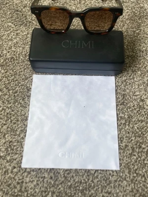 Bruna CHIMI solglasögon  - Snygga solglasögon från CHIMI med brunmelerad båge i klassisk retroform. Kommer med originalfodral och putsduk. Perfekta för dig som vill ha en stilren accessoar med trendig känsla. Knappast använda.