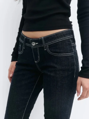 Mörkblå bootcut jeans med kontrastsömmar - Snygga mörkblå bootcut jeans med vita kontrastsömmar och låg midja. Jeansen har klassisk femficksdesign och är tillverkade i ett stretchigt denimtyg som ger en bekväm passform. Perfekta för en trendig och avslappnad look.