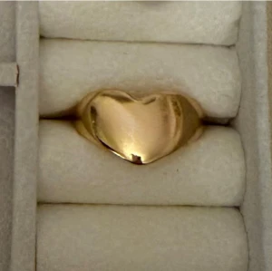 Guldfärgad hjärtformad ring - Säljer en snygg guldfärgad ring med ett hjärtformat motiv. Ringen har en blank, polerad yta och en modern, chunky design som verkligen sticker ut. Perfekt för dig som vill addera lite extra kärlek till din stil.