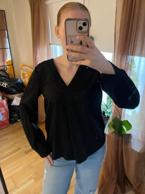 Svart blus med v-ringning från Object - Snygg svart blus från Object med v-ringning och långa ärmar. Blusen har en enkel och stilren design som passar perfekt till jeans eller kjol. Fint skick!