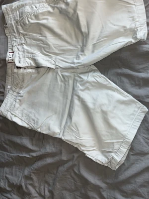 Vita shorts från Jack and Jones  - Snygga vita shorts från Jack and Jones med klassisk passform. De har fickor både fram och bak samt diskret logodetalj bak. Perfekta för sommaren och tillverkade i mjuk bomull för en bekväm känsla.