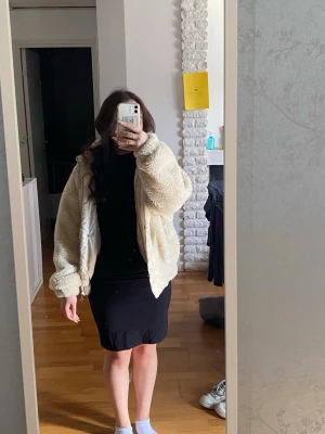 Krämvit teddyjacka med dragkedja från Trendydol - Mysig krämvit teddyjacka i fluffigt material med dragkedja framtill och två sidofickor. Jackan har en avslappnad passform och ribbade muddar vid ärmsluten. Perfekt för att hålla värmen och ge en trendig look. Missfärgning på insidan vid kanten längst ner, vet inte vad det är för något eller om det går att ta bort, se sista bilden, inget som syns jättemycket på utsidan. Storlek S. Har katter hemma!!