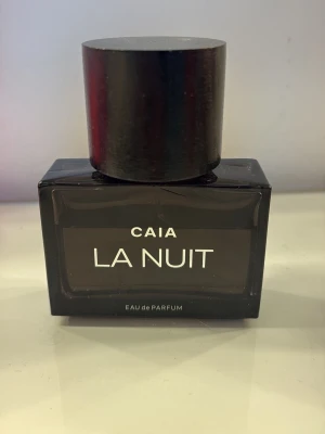 CAIA La Nuit Eau de Parfum - Säljer en elegant parfym från CAIA med namnet La Nuit. Texten på flaskan är vit och designen känns lyxig och modern. Perfekt för dig som gillar exklusiva dofter.