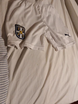 Vita Serbien fotbollsshorts Puma - Säljer ett par vita fotbollsshorts från Puma med Serbiens landslagsemblem på vänster ben. Shortsen har elastisk midja och är tillverkade i ett lätt och svalt material som passar perfekt till träning. Etiketten har tvättats många gånger så det går inte att se vad som står. Priset kan diskuteras.