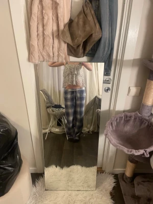 Blommig volang blus med knyt - Söt blommig blus i vitt och grått med volangdetaljer och knyt framtill. Blusen är ärmlös och har en luftig, croppad passform som ger en avslappnad och trendig look. Perfekt för dig som gillar romantiska och feminina toppar.