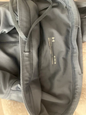 Grå leggings från Under Armour - Snygga grå leggings från Under Armour med dragsko i midjan och tight passform. Tillverkade i ett stretchigt funktionsmaterial som passar perfekt till träning eller chill. Diskret logga på insidan av linningen och sömmar som ger en sportig look.