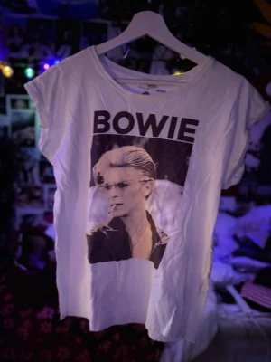 Vit Bowie t-shirt🤍 - vit t-shirt med stort svartvitt Bowie-tryck på framsidan. T-shirten har rund hals och korta ärmar.