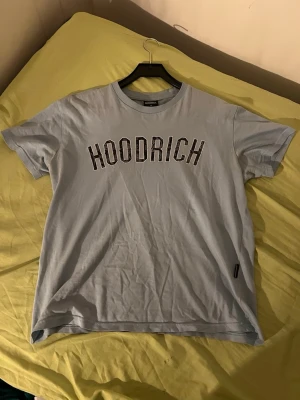 Ljusblå t-shirt - Snygg ljusblå t-shirt med svartvit logga tryckt över bröstet. Klassisk passform med rund halsringning och korta ärmar. Perfekt för en avslappnad streetwear-look.