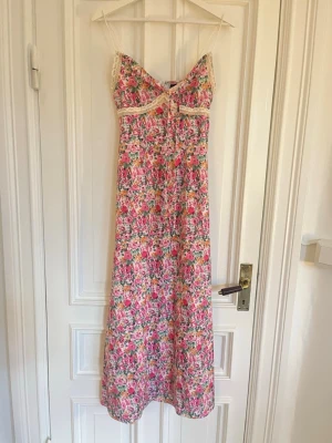 Blommig långklänning med spetsdetaljer - Jättefint lång blommig klänning med spets detalj och smala band. Perfekt till sommaren