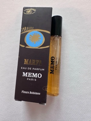 Memo Paris Marfa Eau de Parfum - Upptäck Marfa Eau de Parfum från Memo Paris. Parfymen kommer i en smidig glasflaska med svart kork och har en elegant förpackning i svart med guld- och blådetaljer. Doften är inspirerad av bohemiska blommor och har en exklusiv känsla.