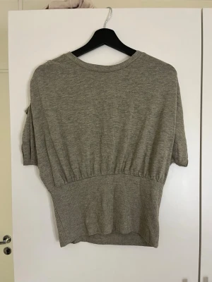 Grå loose-fit topp med ribbad midja - Säljer en grå topp med lös passform upptill men sitter tajt och fint i midjan