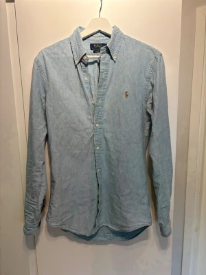 Ljusblå skjorta från Polo Ralph Lauren - Klassisk ljusblå skjorta från Polo Ralph i Bomulls material med jeans struktur. Riktigt bra skick och fet nu till sommaren. Storlek S! Skriv vid minsta fundering!