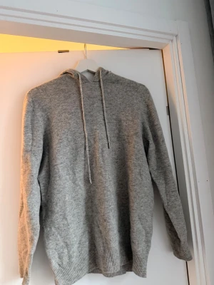 Grå cashmere hoodie - En stilren ljusgrå hoodie med huva och dragsnören. Tillverkad i ett mjukt, stickat material som känns skönt mot huden. Hoodien har ribbade muddar vid ärmslut och nederkant för en snygg passform. Perfekt för dig som gillar en enkel och clean look. Hör av er vid frågar eller liknade. Kan gå ner i pris vid snabb affär. Mvh Mille 